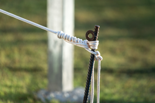 Close-up at rope and steel rod connection which is install to anchor the camping tent part. Camping recreation object photo.