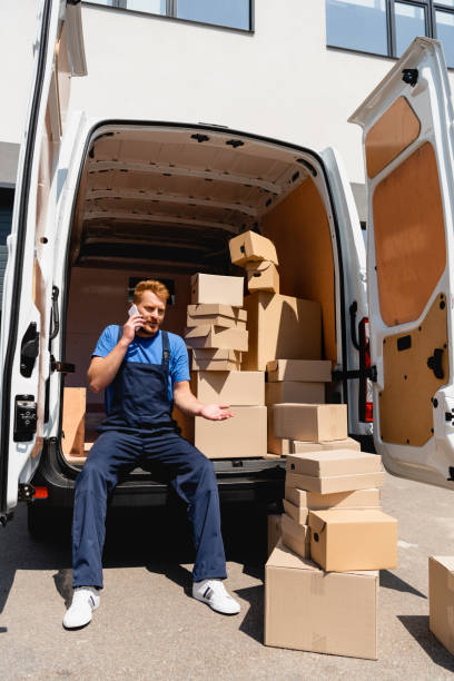istock Loader pointing with hand while talking on smartphone near carton boxes and truck on urban street 1268454267