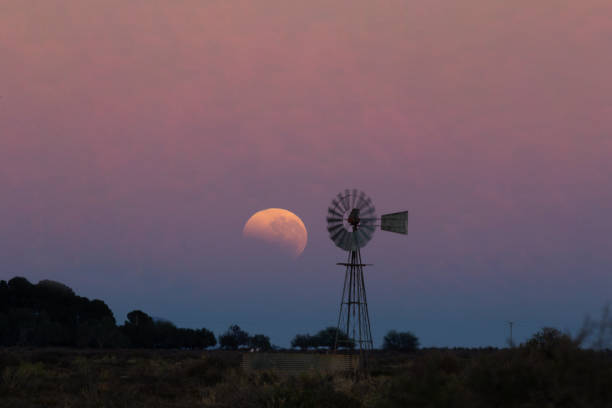 una luna de sangre se pone detrás de una silueta de un viento de viento - the karoo fotografías e imágenes de stock