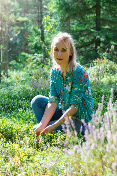 istock Blonde woman collecting cranberries in forest 1268464532
