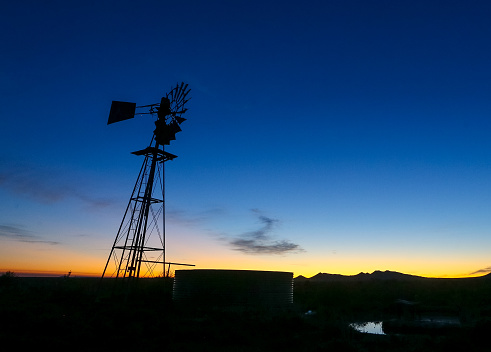 Sunrise with a silhouette of a windpomp in the foreground. Image taken in the Karoo, South Africa.windpomp