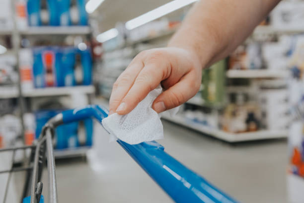 A new normal. Closeup of man hand cleaning shopping cart handle with disinfecting wet wipe. Precaution against virus spread. COVID-19 coronavirus epidemic danger concept. nueva normalidad. primer plano de la manija del carro de la compra de limpieza manual del hombre con la desinfección de la toallita húmeda. precaución contra la propagación del virus. concepto de peligro de epidemia de coronavirus covid-19.