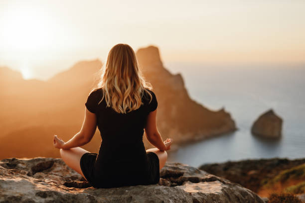 Young meditating girl in the mountains stock photo