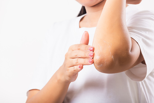 Closeup young Asian woman applies lotion cream on her elbow, studio shot isolated on white background, Healthcare medical and hygiene skin body care concept