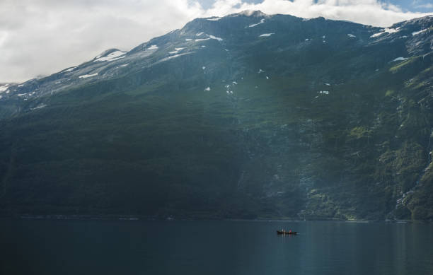 istock Tiny boat in front of massive mountain in Norway. 1268469732