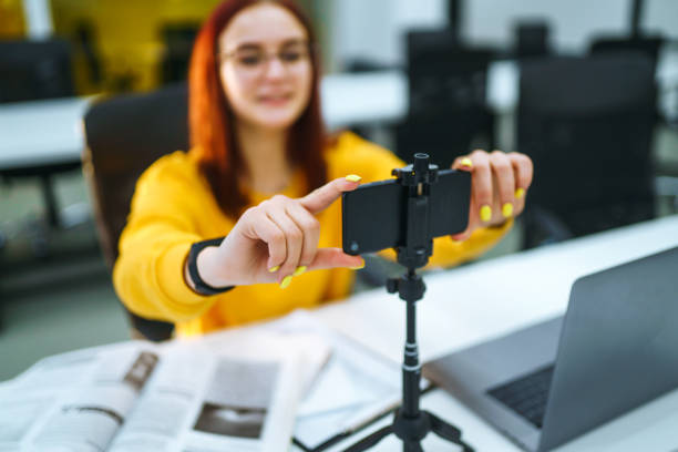 istock Hand woman holding camera for recording video while sitting at office. 1268470824
