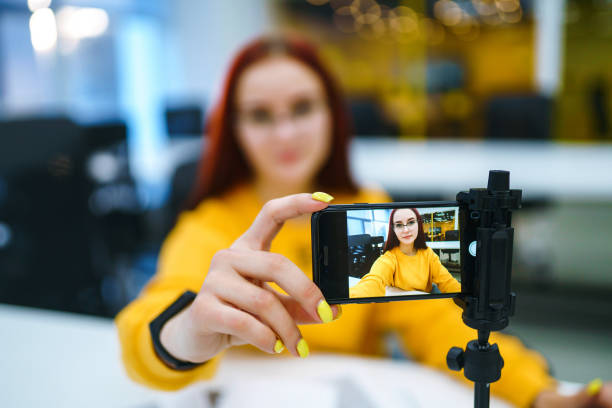 Hand woman holding camera for recording video while sitting at office.