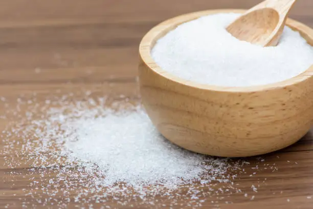 Monosodium glutamate ( MSG ) in wooden bowl isolated on wood table background.