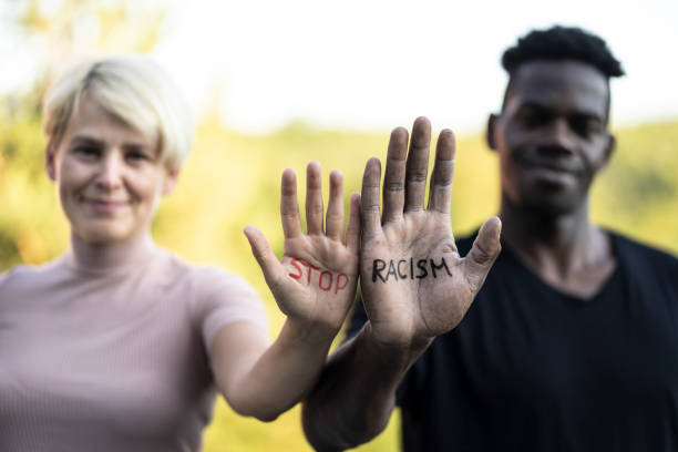 Stop racism slogan written on the hands of two multiethnic friends Multiethnic friends holding their hands with written slogan "Stop racism" racial equality stock pictures, royalty-free photos & images