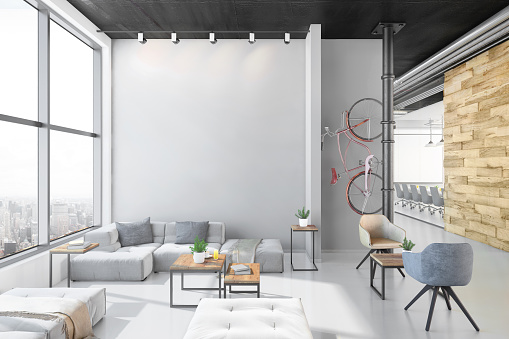 Contemporary open plan office interior with waiting room. Lobby with reception desk, pendant lamp, armchairs and coffee table with sofa. Corridor with concrete ceiling, window, wooden wall and bicycle. Template for copy space. Render.