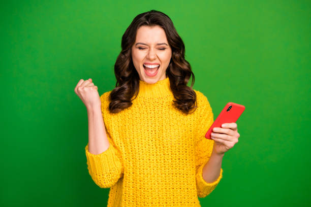 Portrait of delighted energetic girl use smartphone achieve hundred followers on social media raise fists scream yes wear winter style sweater isolated over bright shine color background Portrait of delighted energetic girl use smartphone achieve hundred, followers on social media raise fists scream yes wear winter style sweater isolated over bright shine color background excited woman yellow stock pictures, royalty-free photos & images