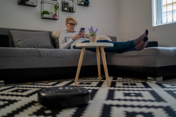 istock One woman, at home, using smartphone, while robot vacuum cleaner is working 1268486242