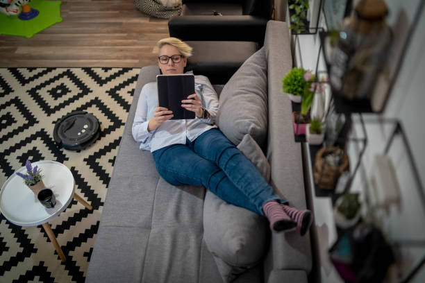 istock One woman, at home, using smartphone, while robot vacuum cleaner is working 1268486458