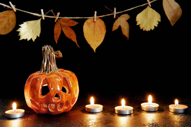 istock Halloween ceramic pumpkin jack lantern and candles on black background. Greeting card 1268486692