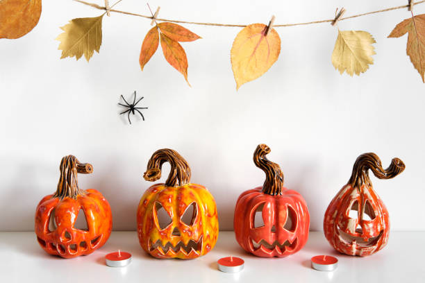 istock Halloween composition with ceramic pumpkins jack lantern and candles on table wall background. Home decoration 1268486696