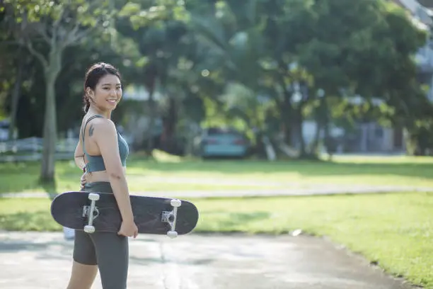 Photo of Chinese teenager is getting ready to play her skateboard at public park.