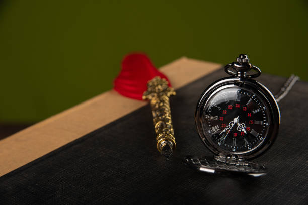istock Fountain pen with red feather, an old watch and a notebook with green background, selective focus. 1268490051