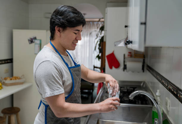 istock Happy young man at home doing the dishes in the kitchen 1268490185