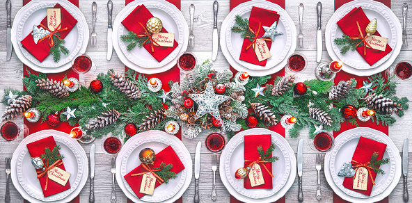 Christmas holidays table setting concept - wine glasses and tableware for festive dinner at home