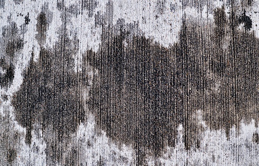 Vehicular oil stains on a concrete driveway from aerial view. Full frame concept image with copy space.