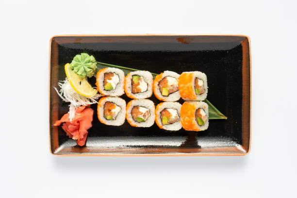 istock A portion of maki sushi with an assortment of Japanese side dishes in a rectangular ceramic plate on a white plate. Top view. 1268492018