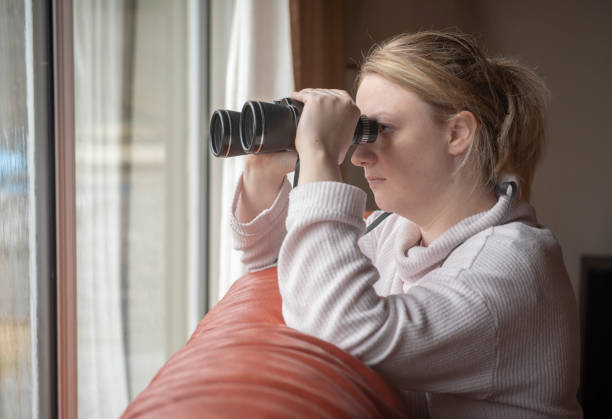 nosy neighbor spying through window with binoculars nosy neighbor spying through window at home with binoculars neighborhood crime watch stock pictures, royalty-free photos & images