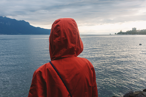Young woman in a rain coat in front of Lake Geneva in Switzerland