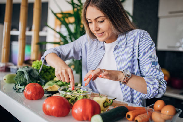 istock Young woman preparing a vegan salad in kitchen 1268503356