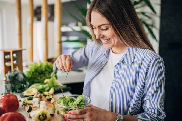 istock Young woman preparing a vegan salad in kitchen 1268503580
