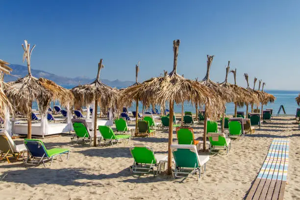 Straw beach umbrellas and sun chairs on a sandy beach on the east coast of Zakynthos island in Greece