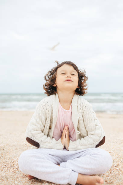 istock little girl meditating on the beach 1268504463