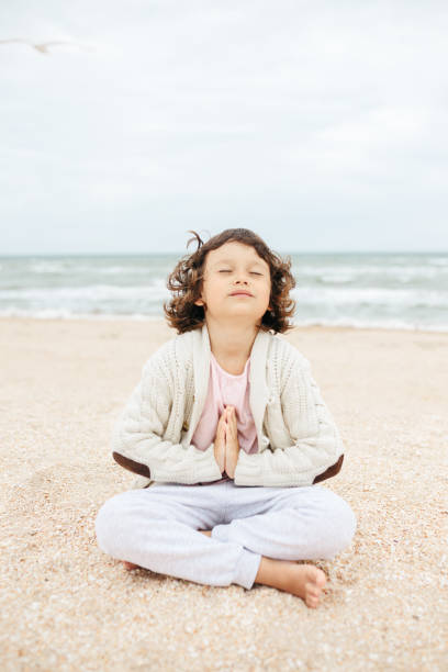 istock little girl meditating on the beach 1268505288