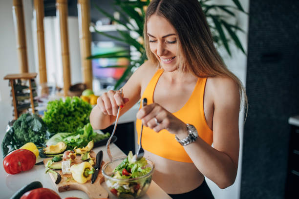 Fit woman making healthy vegetable salad for breakfast