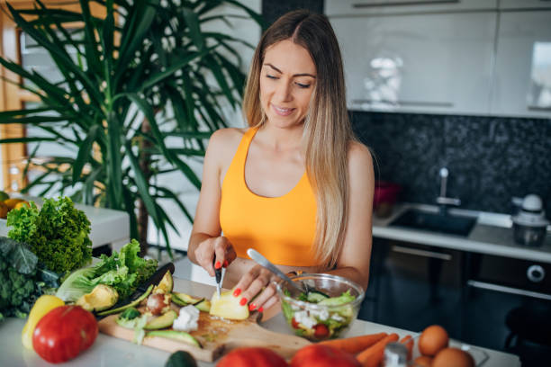 istock Young fit woman making healthy vegetable salad for breakfast 1268505687