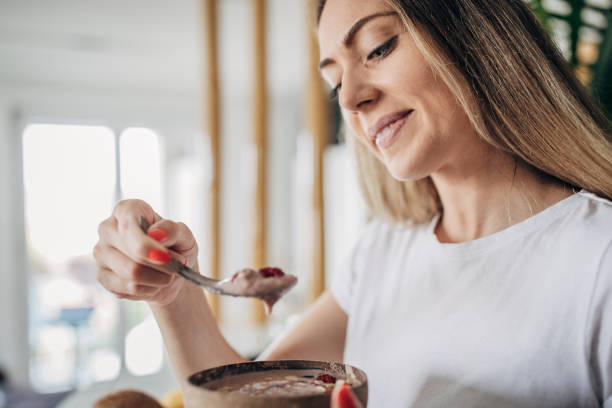 istock Beautiful woman eating her smoothie in a bowl for breakfast 1268505708