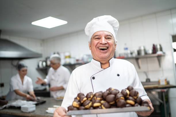 happy senior chef carrying a tray full of eclairs - pastry crust imagens e fotografias de stock
