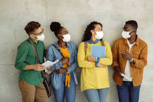 istock Multi-ethnic group of college students with face masks communicating against the wall. 1268508814