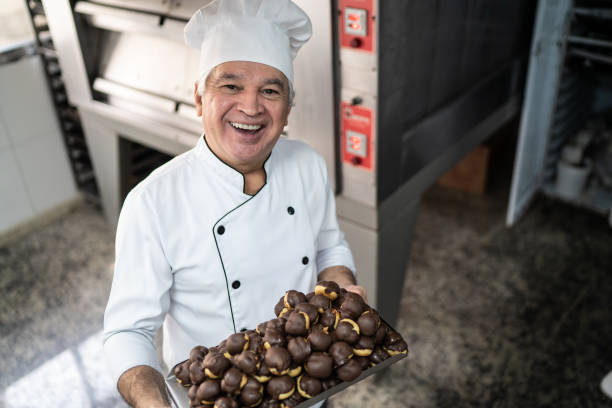 istock Happy senior chef carrying a tray full of eclairs 1268509936