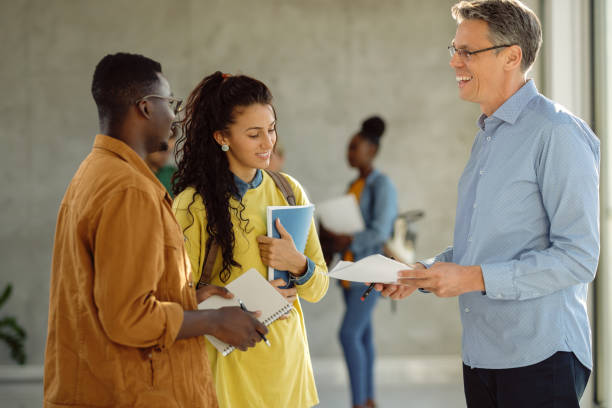 istock Happy university teacher talking to his students in a hallway. 1268510406