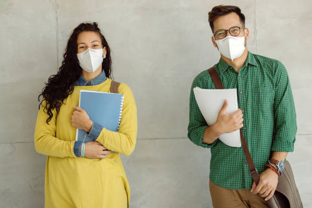 istock Happy students with protective face masks against the wall at the university. 1268512086