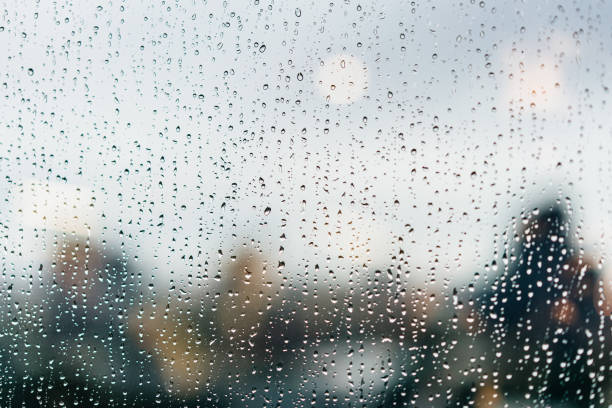 istock Raindrops on windows glass in the dusk with the reflected traffic lights and blur highrise buildings in the background. 1268512276