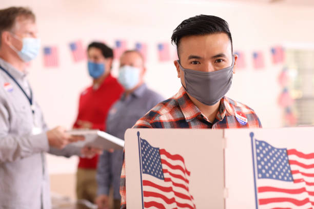 istock Asian descent man votes in USA election wearing mask. 1268512967