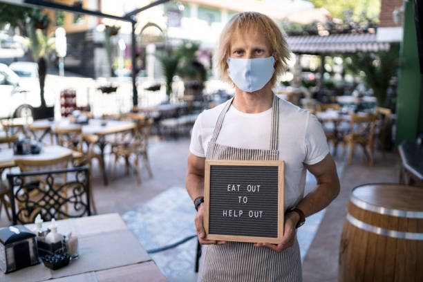 istock Man holding sign Eat out to help out 1268513126