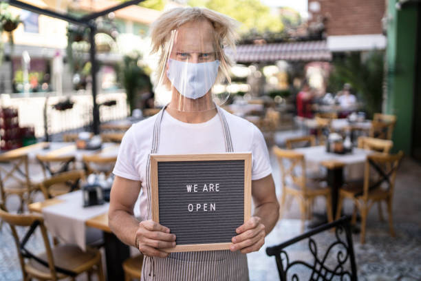 istock Waiter holding WE ARE OPEN sign 1268513142