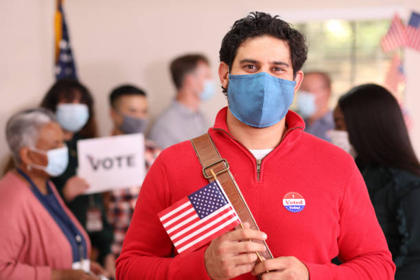 istock Latin descent man votes in USA election wearing mask. 1268513221