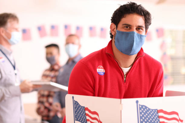 istock Latin descent man votes in USA election wearing mask. 1268513257