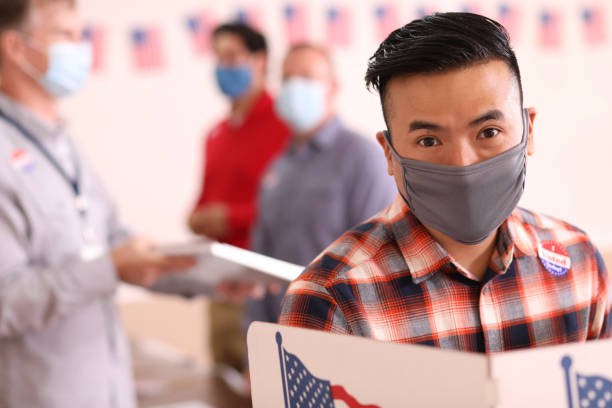 istock Asian descent man votes in USA election wearing mask. 1268513503