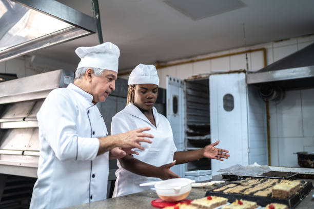 Senior chef explaining something to an assistant Senior chef explaining something to an assistant old candy store stock pictures, royalty-free photos & images