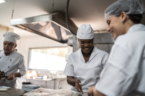 Two chefs preparing brigadeiros in a commercial kitchen