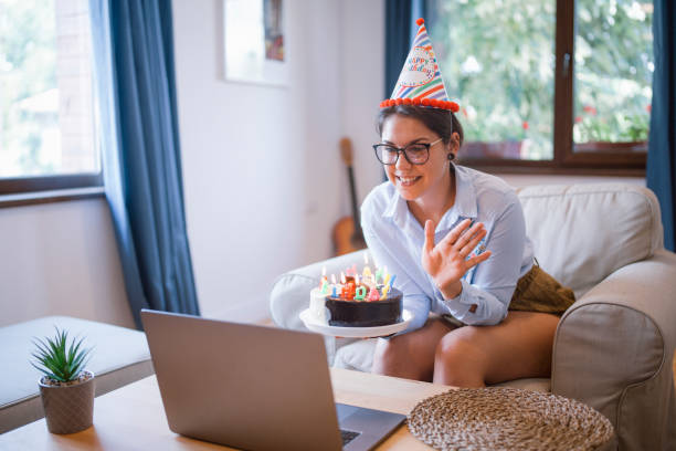 Young Beautiful Female Is Having Online Birthday party Young Cheerful female is having a video call Birthday party virtual birthday celebration stock pictures, royalty-free photos & images